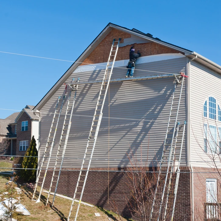 Des ouvriers installant des panneaux d'évitement en plastique sur une maison de deux étages