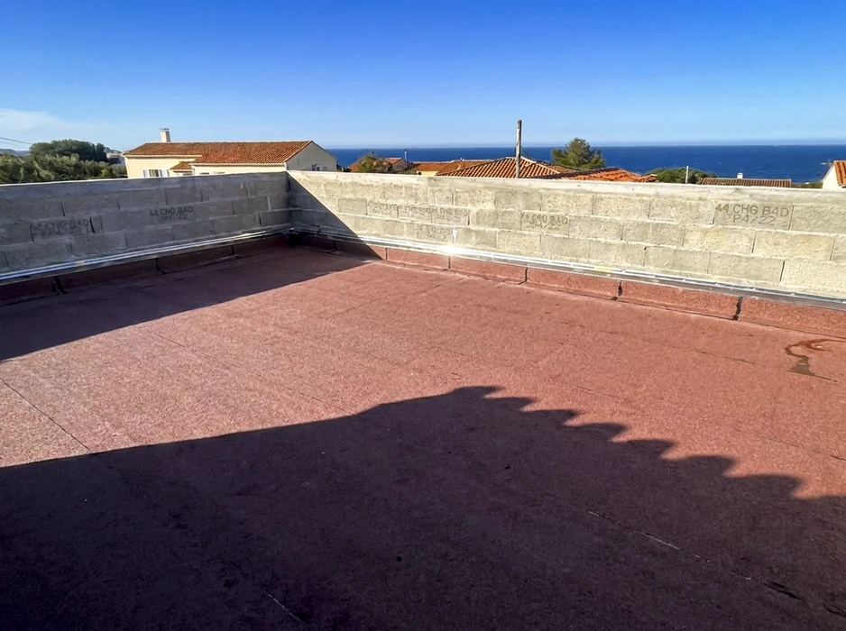 Terrasse-toit plate avec revêtement d'étanchéité bitumineux rouge granulé, en cours de finition