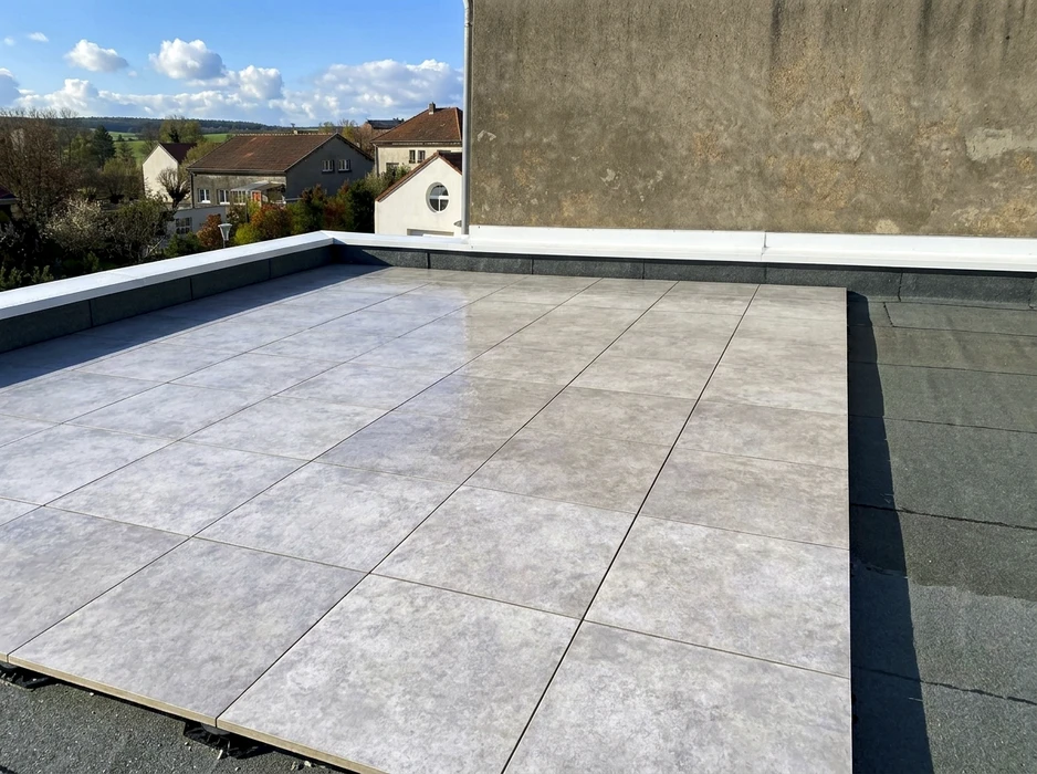 Terrasse sur toiture-terrasse avec carrelage en grès cérame grand format, teinte béton gris clair, pose sur plots ou mortier