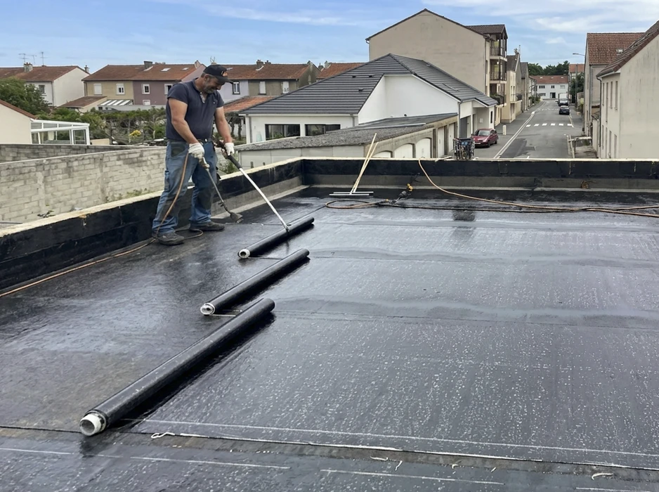 Couvreur appliquant une membrane d'étanchéité bitumineuse sur toiture-terrasse plate par torchage au chalumeau à gaz