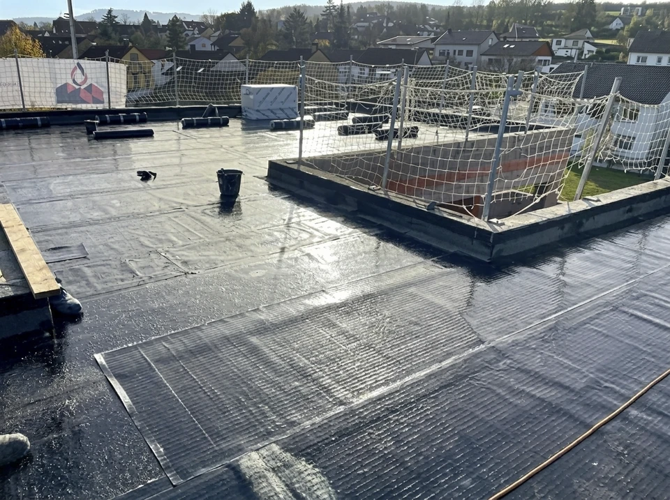 Ouvrier en hauteur effectuant des travaux d'étanchéité sur toiture-terrasse d'un bâtiment industriel