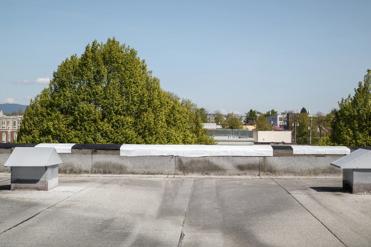Terrasse en béton sur toit d'immeuble urbain avec garde-corps en béton, située entre tours résidentielles modernes