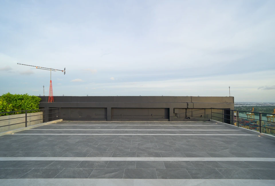 Chantier de construction en extérieur, ouvriers en équipement de protection individuelle installant une membrane d'étanchéité sur toiture-terrasse